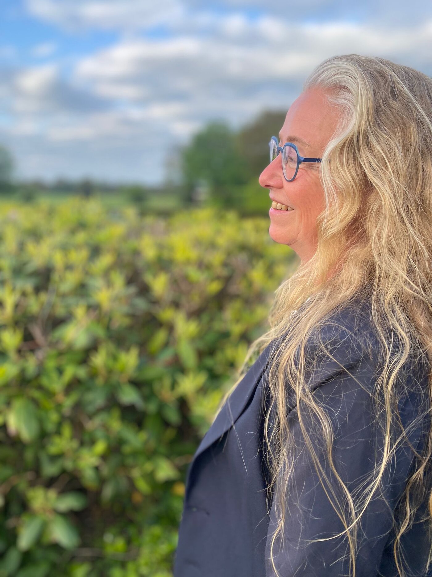 Belinda Scholten buiten bij een heg
