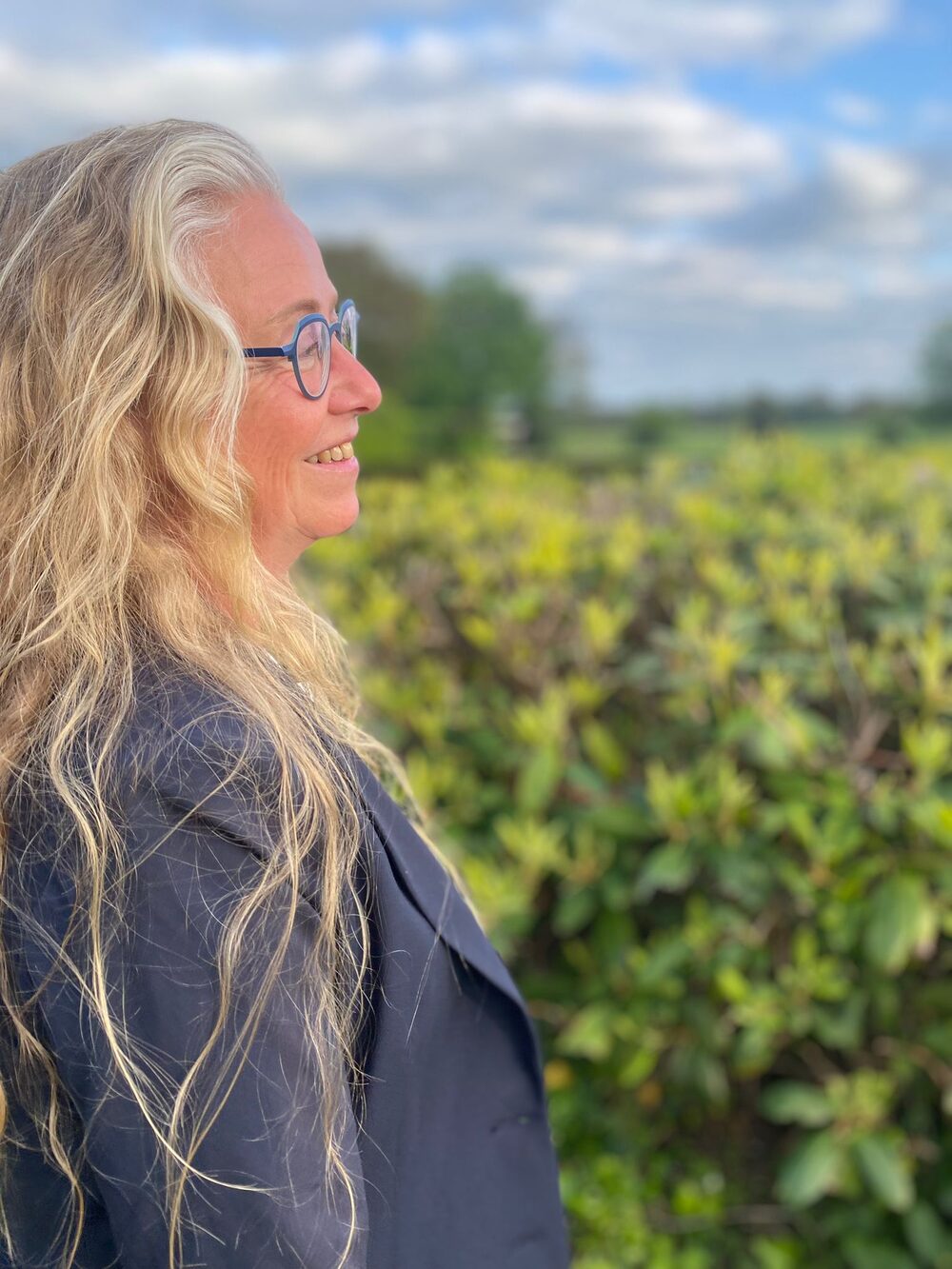 Belinda Scholten buiten bij een heg