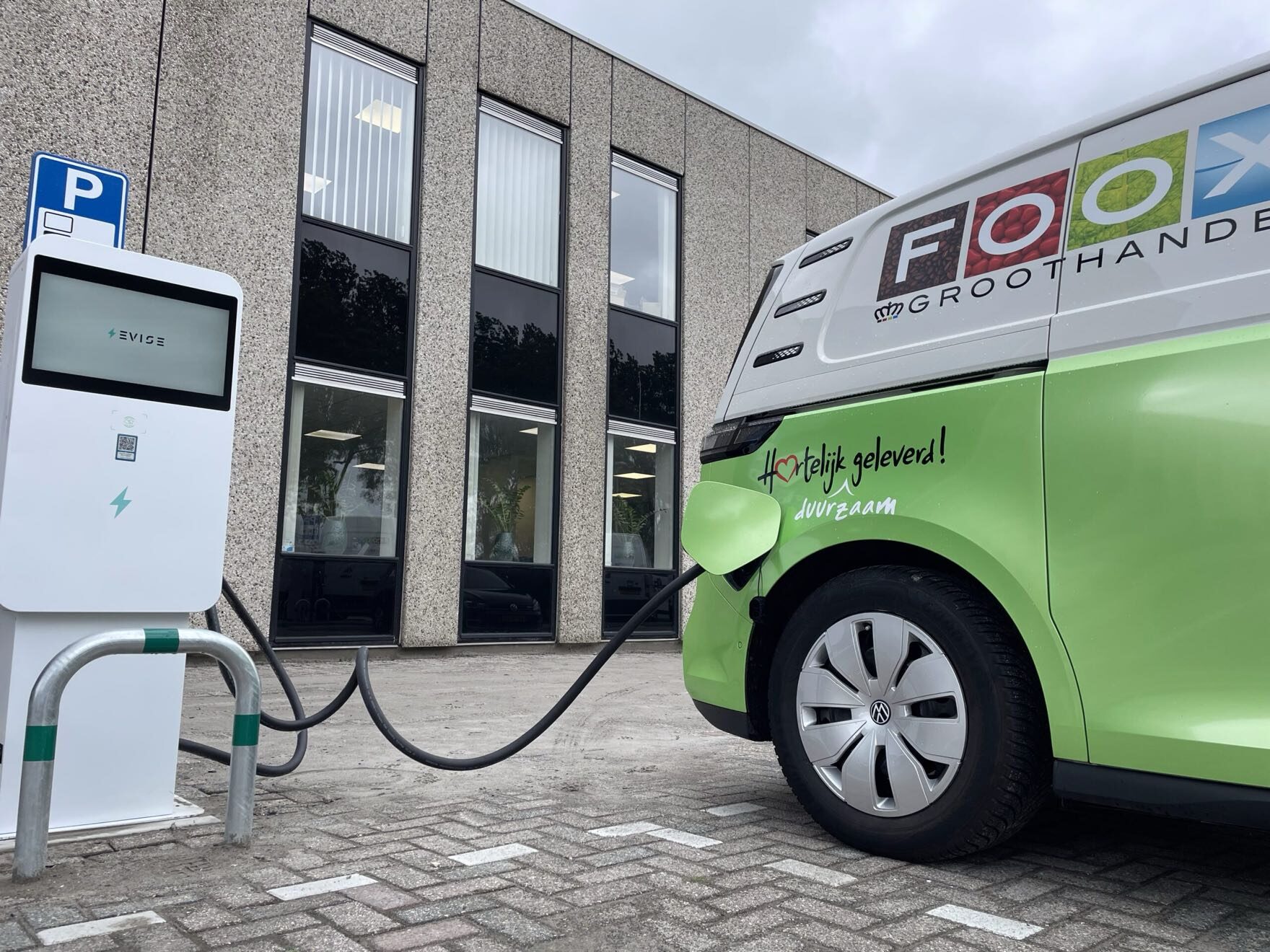 Een Evise-laadpaal laadt een groene elektrische bestelbus op