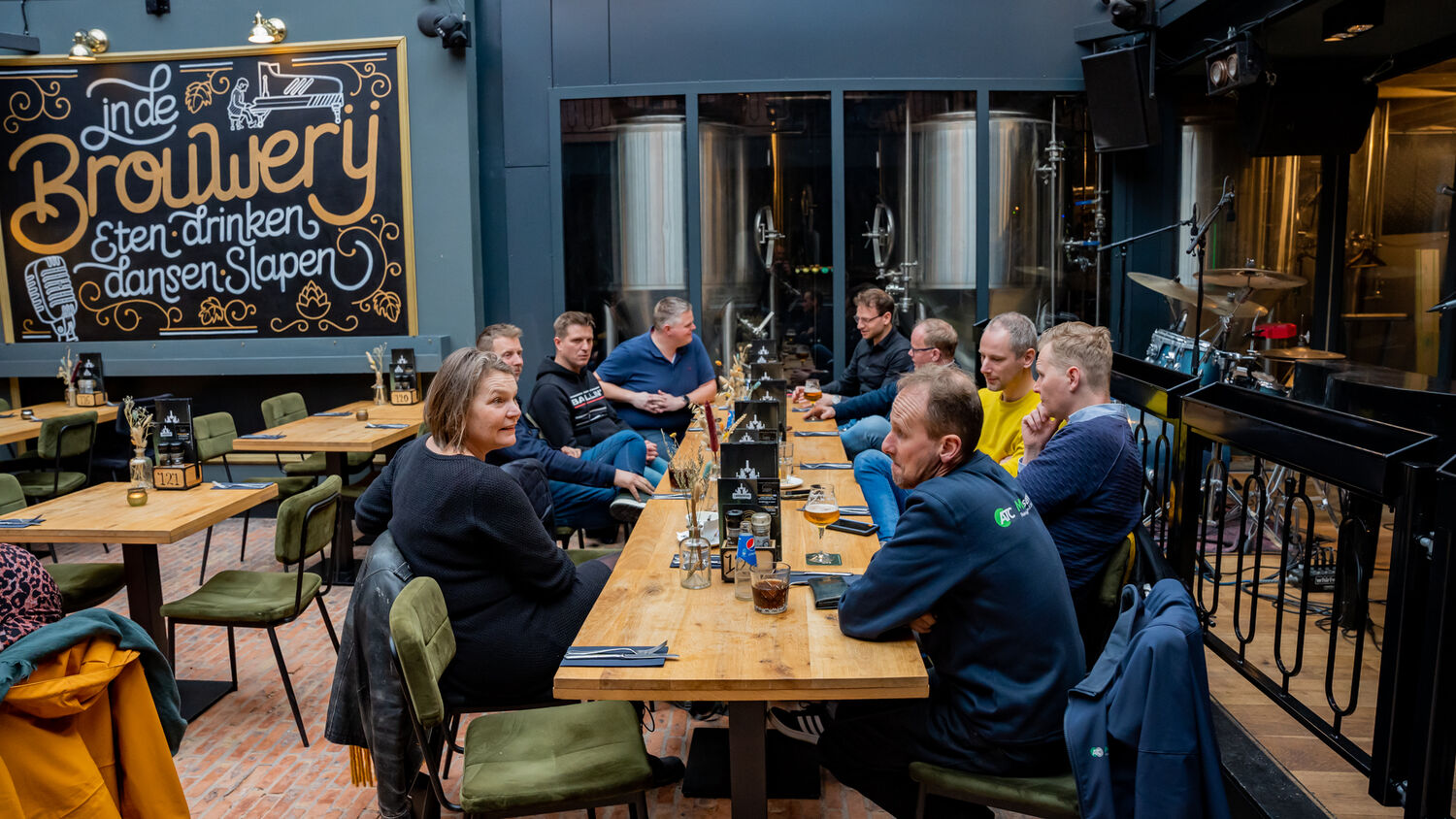 Ondernemers aan tafel in de Brouwerij, met het bord In de Brouwerij op de muur