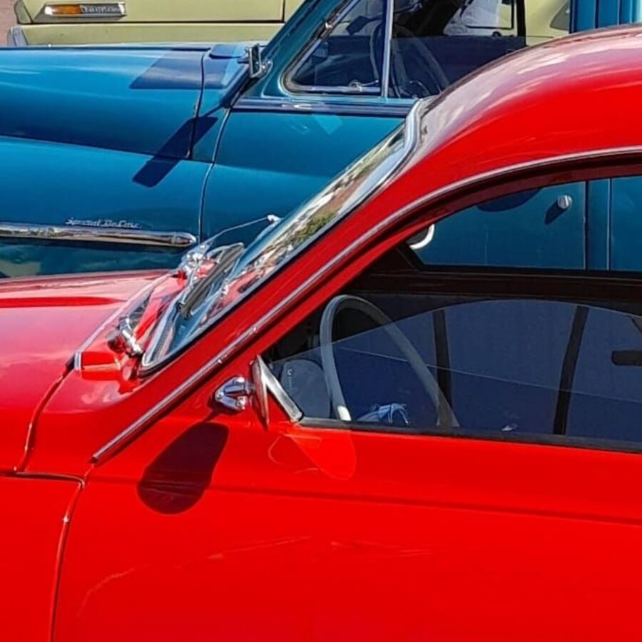 Een blauwe en een rode oldtimer op het plein