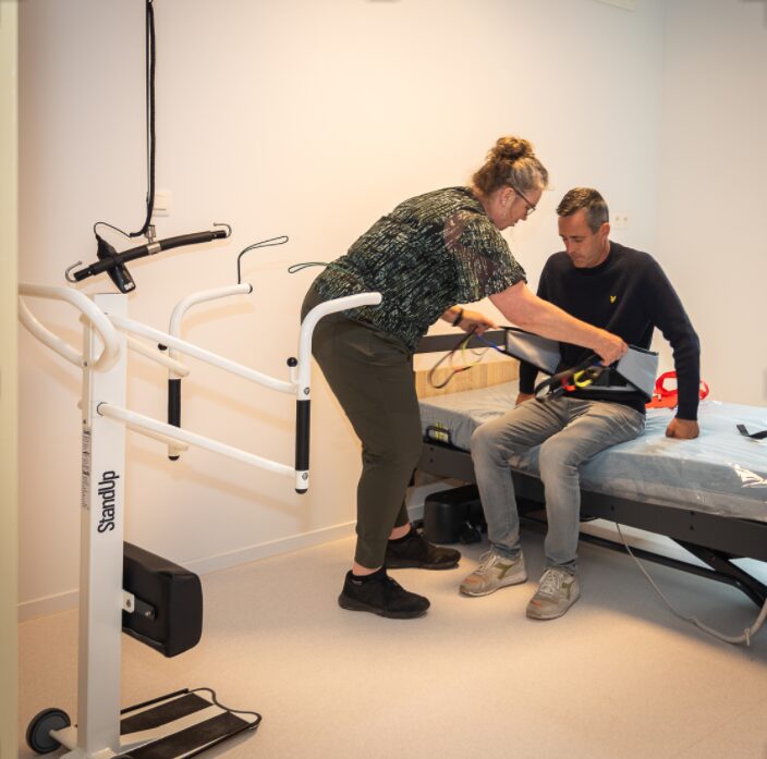 Een zorgverlener helpt iemand met een StandUp-lift